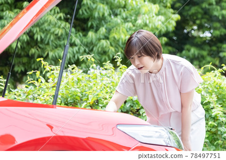 打開一輛破汽車的引擎蓋並檢查它的女人 打開一輛破汽車的引擎蓋並檢查它的女人 78497751