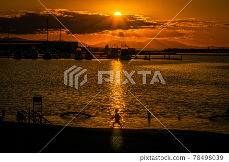 站在夕陽西下的碼頭上的人影和遠景 78498039