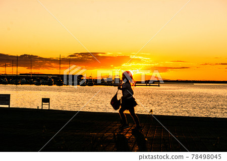 站在夕陽西下的碼頭上的人影和遠景 78498045