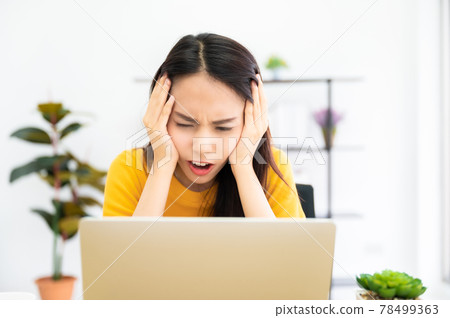 Asian young woman seriously working on computer laptop in house Asian young woman seriously working on computer laptop in house 78499363