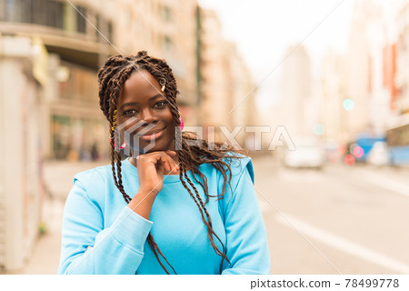 Pretty young black woman in the middle of the city, smiling at camera. 78499778