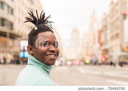 Young black man in the middle of the city, smiling. 78499780