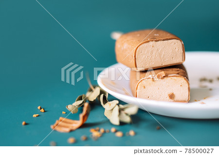 Chocolate Popsicles cut with filling lying on top of each other and white plate on cian background Chocolate Popsicles cut with filling lying on top of each other and white plate on cian background 78500027