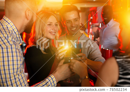 Young positive cheerful people with cocktails having fun at nightclub Young positive cheerful people with cocktails having fun at nightclub 78502234