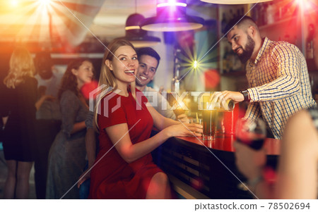 Portrait of happy young woman with colleagues enjoying corporate party in the bar Portrait of happy young woman with colleagues enjoying corporate party in the bar 78502694