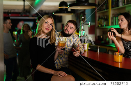 Charming girl flirts with a man in night bar Charming girl flirts with a man in night bar 78502743