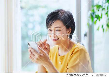 A middle woman who operates a smartphone in the living room 78504067