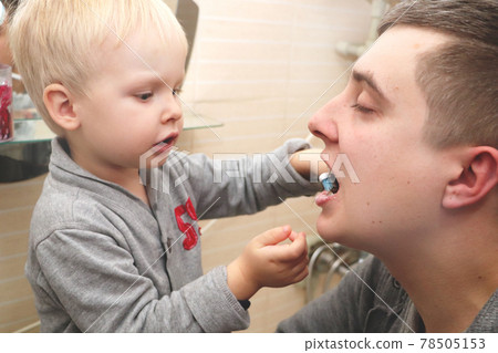 Dad and son brush their teeth in the bathroom. Father Brushing Teeth to Child 78505153