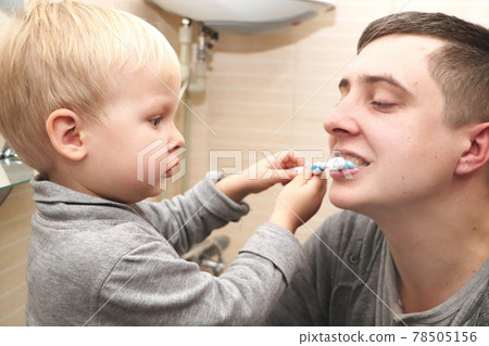 Dad and son brush their teeth in the bathroom. Father Brushing Teeth to Child 78505156