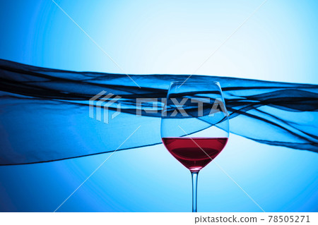 Glass of red wine on a background of waving curtain. Glass of red wine on a background of waving curtain. 78505271