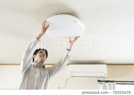 Male electrical worker installing a ceiling light Male electrical worker installing a ceiling light 78505676
