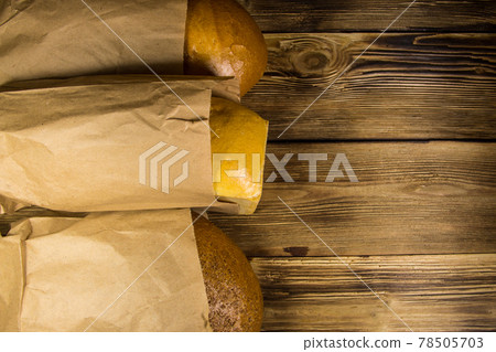 Assortment of bread packed in paper on wooden table Assortment of bread packed in paper on wooden table 78505703