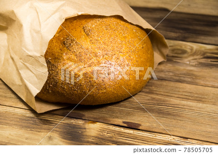 Bread packed in paper on wooden table Bread packed in paper on wooden table 78505705