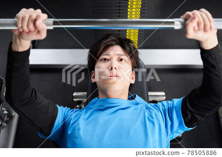 Young man doing weight training with a machine 78505886