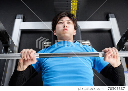 Young man doing weight training with a machine 78505887