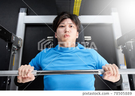Young man doing weight training with a machine 78505889