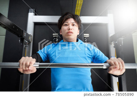 Young man doing weight training with a machine 78505890