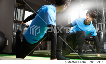 Young man stretching in front of a mirror Young man stretching in front of a mirror 78505914