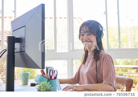 A woman working on a PC with headphones 78506738