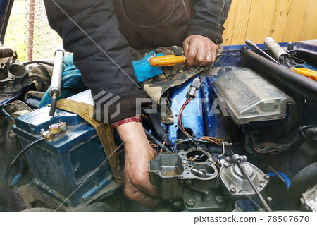 Adjustment of the motors' valves on a by an auto locksmith in a garage, dirty hands. Adjustment of the motors' valves on a by an auto locksmith in a garage, dirty hands. 78507670