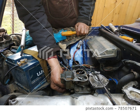 Adjustment of the motors' valves on a by an auto locksmith in a garage, dirty hands. Adjustment of the motors' valves on a by an auto locksmith in a garage, dirty hands. 78507671