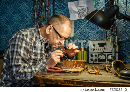 Man repairing an old radio receiver Man repairing an old radio receiver 78508240