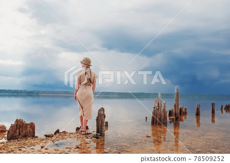 Woman traveler in a hat and beige dress outdoors. 78509252