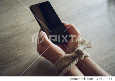 Tied female hands are holding a mobile phone. Mobile phone addic 78509253