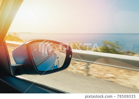 Close-up of side mirror of the moving car with reflection of the sea Close-up of side mirror of the moving car with reflection of the sea 78509335