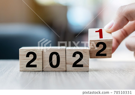 Businessman hand holding wooden cube with flip over block 2021 to 2022 text on table background. Resolution, strategy, solution, goal, business and New Year holiday concepts 78510331