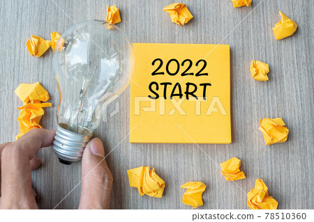2022 Start words on yellow note and crumbled paper with Businessman holding lightbulb on wooden table background. New Year New Idea Creative, Innovation, Imagination, Resolution and Goal concept 2022 Start words on yellow note and crumbled paper with Businessman holding lightbulb on wooden table background. New Year New Idea Creative, Innovation, Imagination, Resolution and Goal concept 78510360