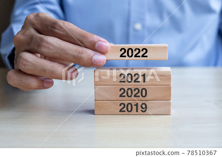 Businessman hand pulling 2022 wooden building blocks on table background. Business planning, Risk Management, Resolution, strategy, solution, goal, New Year New You and happy holiday concepts Businessman hand pulling 2022 wooden building blocks on table background. Business planning, Risk Management, Resolution, strategy, solution, goal, New Year New You and happy holiday concepts 78510367