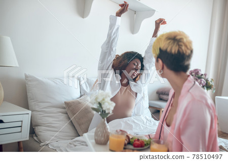 Awakening dark-skinned woman and caucasian girlfriend with breakfast tray Awakening dark-skinned woman and caucasian girlfriend with breakfast tray 78510497