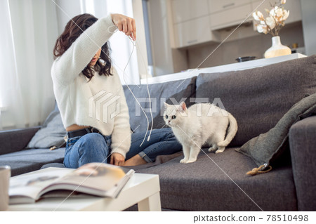 A woman in a white sweater playing with her cute pet A woman in a white sweater playing with her cute pet 78510498