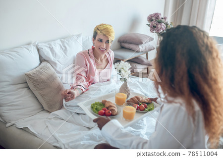 Happy woman in bed and girlfriend with breakfast Happy woman in bed and girlfriend with breakfast 78511004