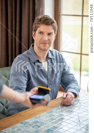 Man holding out smartphone to pos terminal 78511048