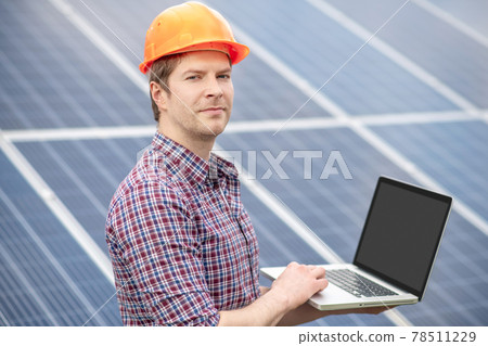 Young man in helmet working with laptop outdoors Young man in helmet working with laptop outdoors 78511229