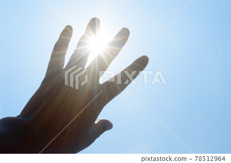 Hot summer sunlight rays pouring through human hand. Hand covering sun light heat temperature. Protection from ultraviolet light and sunburn background. Sunstroke, heatstroke, greenhouse effect. 78512964