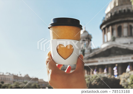 paper cup of natural coffee with carved white heart in woman's palm on background of Saint Isaac's Cathedral in St. Petersburg in blur paper cup of natural coffee with carved white heart in woman's palm on background of Saint Isaac's Cathedral in St. Petersburg in blur 78513188