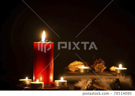 Red Candle with fire against defocused lights in darkness with golden bokeh in the dark Background 78514095