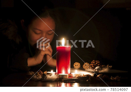 Woman Praying and worship to GOD Using hands to pray in religious beliefs and worship christian with Red Candle with fire against defocused lights in darkness with in the dark Background Woman Praying and worship to GOD Using hands to pray in religious beliefs and worship christian with Red Candle with fire against defocused lights in darkness with in the dark Background 78514097