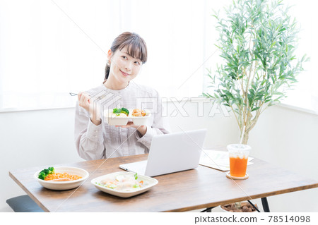 A woman working remotely while eating delivery food A woman working remotely while eating delivery food 78514098