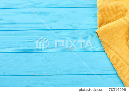 Yellow towel on blue wooden background. 78514996