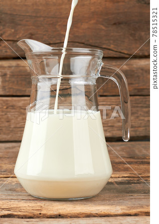 Milk pouring into a jug. 78515321