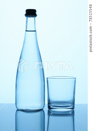 Glass bottle with liquid and glass cup. 78515548