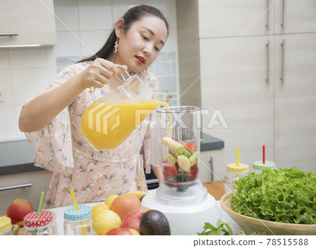 Happy woman enjoy preparing freshly squeezed fruits with vegetables for making smoothies for breakfast together in the kitchen.diet and Health concept. 78515588