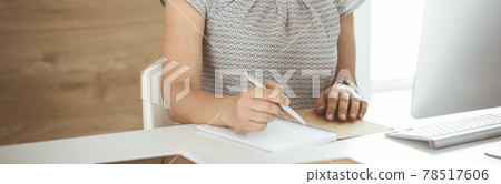 Unknown business woman working with computer while sitting at the desk in modern office, close-up. Middle aged female lawyer or auditor at work 78517606