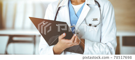 Unknown woman-doctor at work in sunny clinic. Female physician controls medication history record, close-up. Medicine concept Unknown woman-doctor at work in sunny clinic. Female physician controls medication history record, close-up. Medicine concept 78517698