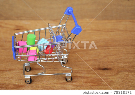 Colorful of rubber cube and other shapes inside toy shopping trolley with wood texture background. Colorful of rubber cube and other shapes inside toy shopping trolley with wood texture background. 78518171