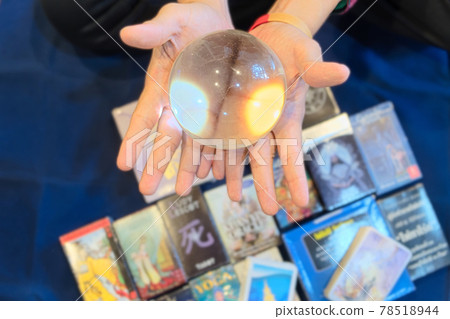 Close-up hands of fortune teller who show clear marble ball for prediction fate on tarot card and wood cube letter blurred background, Divine magic concept, top-view 78518944